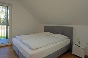 uma cama num quarto branco com uma janela em Hiša Štolc em Gornja Radgona