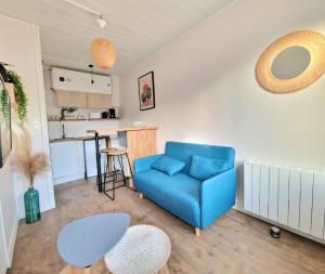 a living room with a blue couch and a kitchen at Cocon cosy au cœur de Verneuil in Verneuil d’Avre et d’Iton