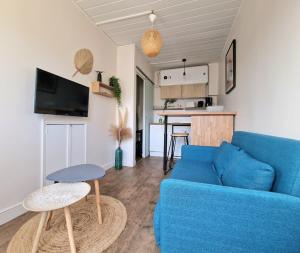 a living room with a blue couch and a kitchen at Maisonnette en Duplex - Cosy- Centre Ville in Verneuil d’Avre et d’Iton