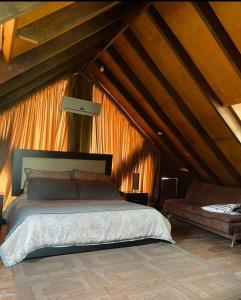 - une chambre mansardée avec un grand lit dans l'établissement Cabaña sierra de lobos, à Las Palomas