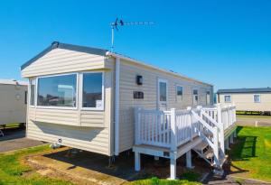 a white tiny house sitting in a parking lot at SP158 - Camber Sands Holiday Park - 3 Bedrooms - Second Toilet - Decking - Private Parking in Camber