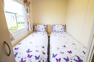 two beds in a small room with butterflies on them at SP158 - Camber Sands Holiday Park - 3 Bedrooms - Second Toilet - Decking - Private Parking in Camber