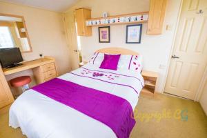 a bedroom with a large bed with purple and white sheets at WW165 - Camber Sands Holiday Park - Sleeps 6 - 2 Bedrooms - 2 Bathrooms in Camber