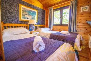 a bedroom with two beds in a log cabin at Five Waterings - Luxury Lodge in Brookland