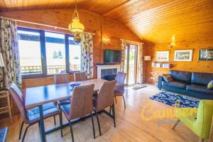 a dining room with a table and a couch at Five Waterings - Luxury Lodge in Brookland