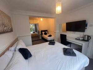 a hotel room with a white bed and a television at Charnwood Regency Guest House in Loughborough