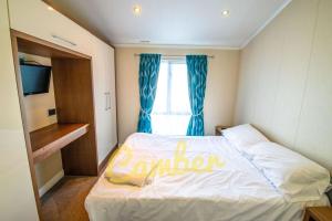 małą sypialnię z łóżkiem z oknem w obiekcie MP768 - Camber Sands Holiday Park - Huge Lodge - Small dog friendly - sleeps 8 w mieście Camber
