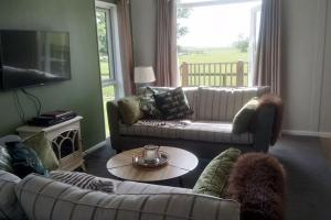 a living room with two couches and a table at Puddledock - luxury lodge - Kent countryside in Brookland