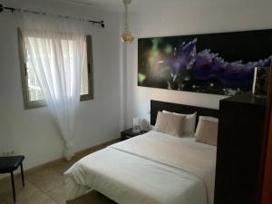 ラ・レスティンガにあるVV Princesa Guayarminaの白いベッドと大きな絵画が壁に描かれたベッドルーム1室
