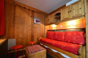 Pokój z czerwoną kanapą i drewnianymi ścianami w obiekcie Résidence Villaret - Studio pour 4 Personnes 234 w Les Menuires