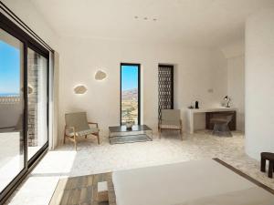 Cette chambre blanche dispose d'une table, de chaises et de fenêtres. dans l'établissement Sun Aeriko, à Tinos