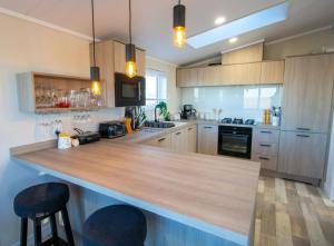 une cuisine avec un grand comptoir en bois et deux tabourets de bar dans l'établissement MP515 - Camber Sands Holiday Park, à Camber