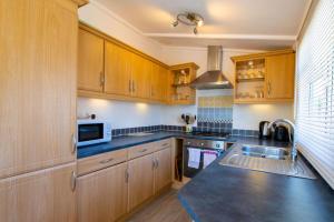 uma cozinha com armários de madeira e um micro-ondas em 11 The Oaks - Lodge - Coghurst Hall - Hastings em Westfield