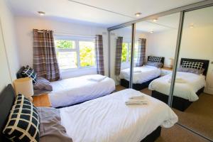 1 Schlafzimmer mit 3 Betten und einem Spiegel in der Unterkunft 11 The Oaks - Lodge - Coghurst Hall - Hastings in Westfield