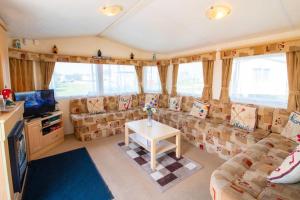 uma sala de estar com sofás, uma televisão e uma mesa em WW213 - 4B - Parkdean Resorts - Camber Sands - Com em Camber