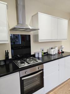 a kitchen with white cabinets and a stove top oven at Charming 4-Bedroom House in Liverpool w/ WiFi - Sleeps 10 by PureStay in Liverpool