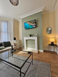 a living room with a fireplace and a tv on the wall at Charming 4-Bedroom House in Liverpool w/ WiFi - Sleeps 10 by PureStay in Liverpool