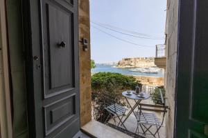 an open door with a table and chairs on a balcony at Harbour Mansion in Birgu