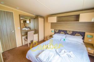 a bedroom with a large white bed with a wooden headboard at MP502 - Camber Sands Holiday Park - Sleeps 6 - Small Dog - Gated Decking - Amazing Marsh Views in Camber