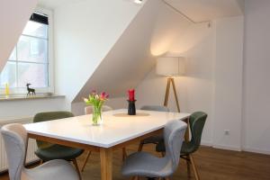 a white table with chairs and a vase of flowers on it at Kormoran Harry´s Place Q8 in Prerow