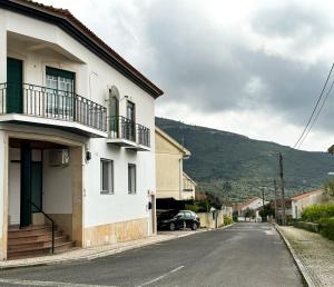 uma casa branca com um carro estacionado numa rua em Largo das Calçadas em Porto de Mós