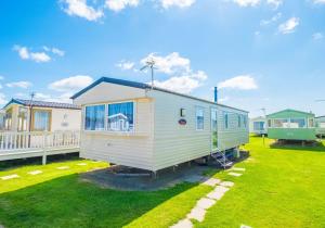 a tiny house on a lawn in front of a house at MP694 - Camber Sands - Sleeps 8 in Camber