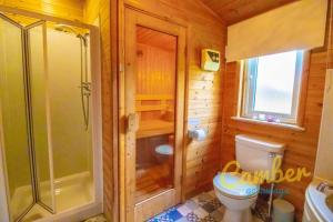 a wooden bathroom with a shower and a toilet at Tore Petty - Romantic lodge - spa bath and sauna in Brookland