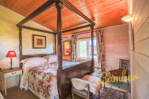 1 dormitorio con cama con dosel en una habitación en Tore Petty - Romantic lodge - spa bath and sauna, en Brookland