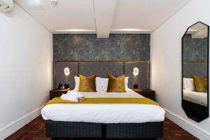 1 dormitorio con 1 cama grande con almohadas amarillas en Cape Diamond Boutique Hotel, en Ciudad del Cabo