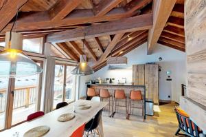 una cucina con soffitti in legno e un tavolo con sgabelli di Chalet L'etable - CHALET | SAINT-MARTIN-DE-BELLEVILLE MAE-4304 a Saint-Martin-de-Belleville