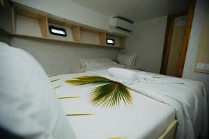 1 dormitorio con 2 camas con sábanas blancas y una planta de palmera en Odyssey of sunny side, en Male