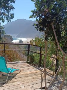 eine Holzterrasse mit einem Stuhl und Meerblick in der Unterkunft Cabaña con Vista al mar Playa grande Quintay in Casablanca