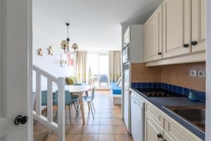 kuchnia z białymi szafkami i stołem z niebieskimi krzesłami w obiekcie Les Appartements aux Restanques du Golfe de St Tropez - maeva Home - Appartement 3 Pièces 6 Personnes - Sélection - vue Mer MAE-6504 w mieście Grimaud