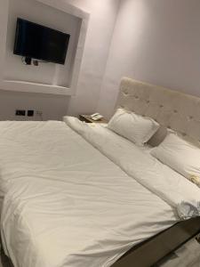 a bed with white sheets and a flat screen tv at California Luxury Hotel & Suite in Ibadan