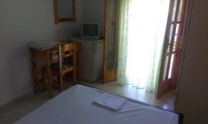 プラタリアにあるVirginia's Roomsのベッド、テレビ、テーブルが備わる客室です。