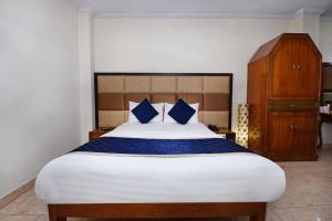 a bedroom with a large bed with blue pillows at City Plaza in Panchkula