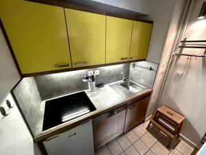 a small kitchen with yellow cabinets and a sink at Résidence Oisans - 2 Pièces pour 6 Personnes 824 in Les Menuires