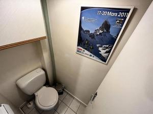 a bathroom with a toilet and a poster on the wall at Résidence Oisans - 2 Pièces pour 6 Personnes 824 in Les Menuires