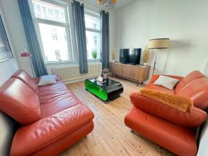 Sala de estar con 2 sofás de cuero y TV en Gemütliche Retro Wohnung, en Bremerhaven