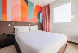 um quarto com uma cama e uma parede colorida em B&B HOTEL Colmar Liberté 4 étoiles em Colmar