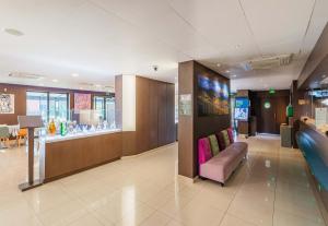 a lobby with a pink couch and a bar at B&B HOTEL Colmar Liberté 4 étoiles in Colmar