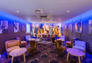 une salle d'attente avec des chaises, des tables et des affiches dans l'établissement B&B HOTEL Colmar Liberté 4 étoiles, à Colmar