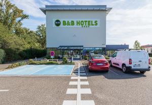 a sign for a bdb hotel with cars parked in a parking lot at B&B HOTEL Colmar Liberté 4 étoiles in Colmar