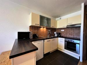a kitchen with white cabinets and a black counter top at Résidence Grande Masse - Appartement pour 5 en bord de piste aux Ménuires MAE-4894 in Les Menuires +12 photos