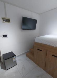 Cosy studio with all amenities في غراند بايَ: غرفة نوم مع سرير وتلفزيون على الحائط