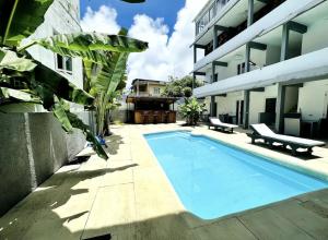 a swimming pool with two benches next to a building at Cosy studio with all amenities in Grand-Baie