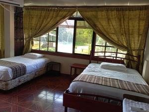 two beds in a room with two windows at Grand Selva Lodge & Tours in Tena