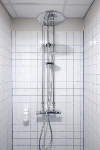 a shower in a bathroom with white tiles at Beach Trail apartments by Daniel&Jacob's in Copenhagen