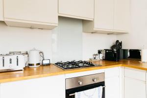 a kitchen with white cabinets and a stove top oven at Charming & Stylish 2-Bed House - 20 min Walk to Centre in Bath