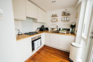 a kitchen with white cabinets and a wooden floor at Charming & Stylish 2-Bed House - 20 min Walk to Centre in Bath